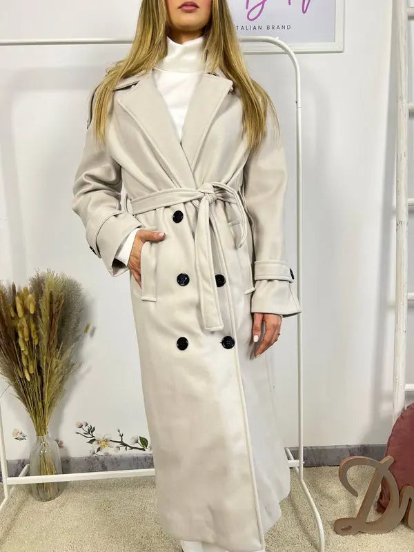 Ce manteau croisé présente une fermeture boutonnée, une ceinture intégrée et des poches pratiques, alliant élégance raffinée et praticité polyvalente.