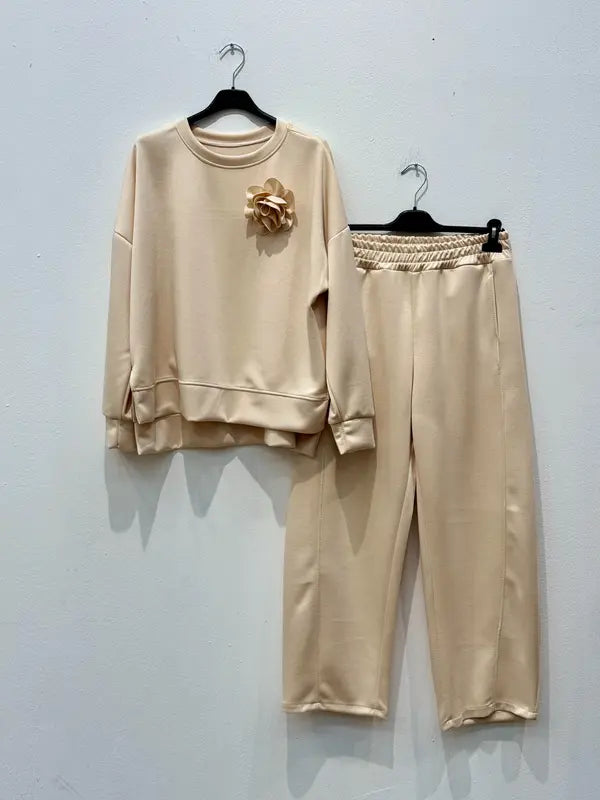 Cet ensemble de combinaison deux pièces, fabriqué en tissu viscose, comprend un haut orné d'une broche en forme de fleur et un pantalon sarouel élastiqué.