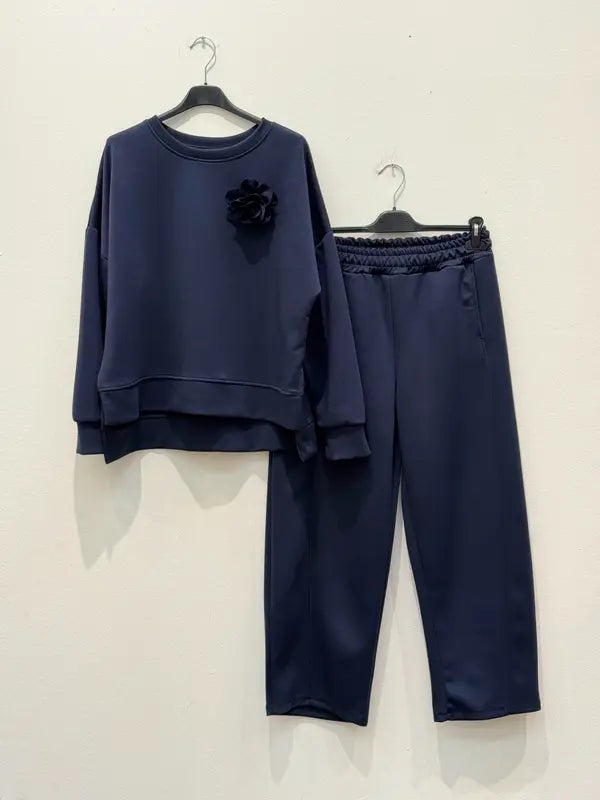 Cet ensemble de combinaison deux pièces, fabriqué en tissu viscose, comprend un haut orné d'une broche en forme de fleur et un pantalon sarouel élastiqué.