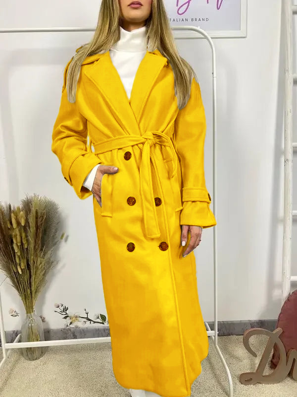 Ce manteau croisé présente une fermeture boutonnée, une ceinture intégrée et des poches pratiques, alliant élégance raffinée et praticité polyvalente.
