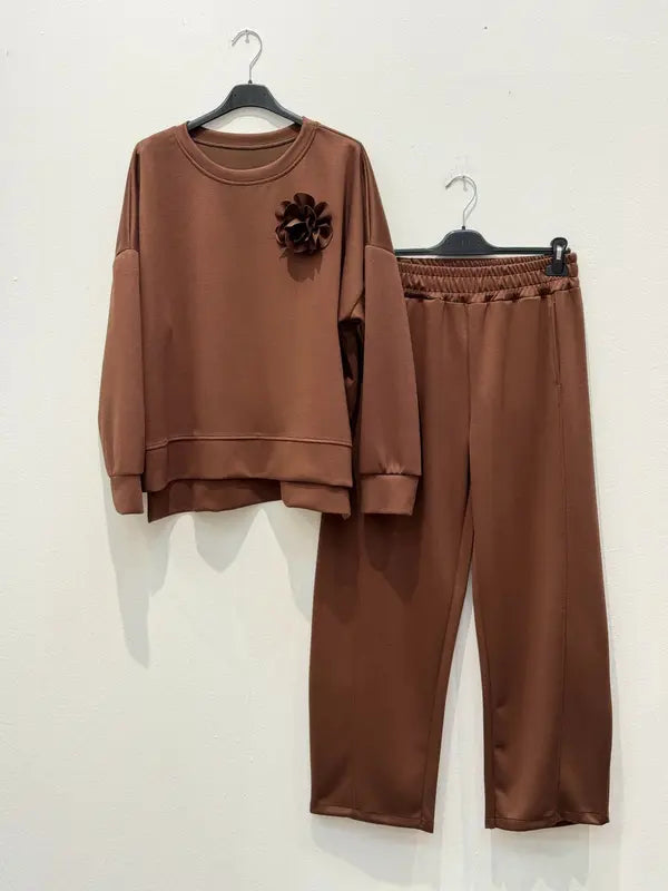 Cet ensemble de combinaison deux pièces, fabriqué en tissu viscose, comprend un haut orné d'une broche en forme de fleur et un pantalon sarouel élastiqué.