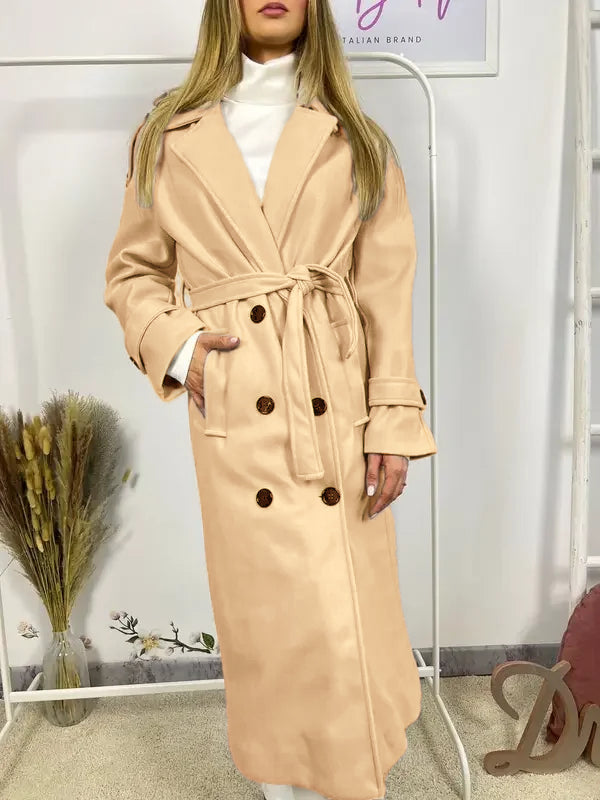 Ce manteau croisé présente une fermeture boutonnée, une ceinture intégrée et des poches pratiques, alliant élégance raffinée et praticité polyvalente.