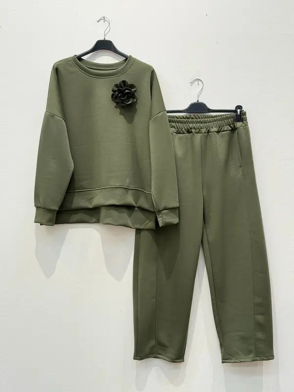Cet ensemble de combinaison deux pièces, fabriqué en tissu viscose, comprend un haut orné d'une broche en forme de fleur et un pantalon sarouel élastiqué.